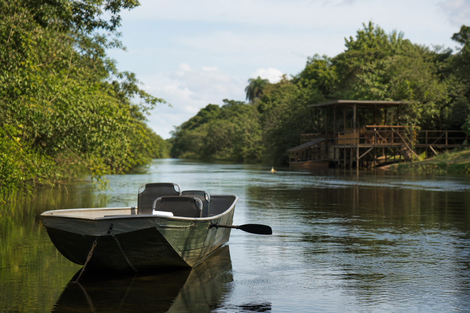 Embarcação navegando em rio da região de Três Lagoas, com vegetação às margens e estrutura turística ao fundo