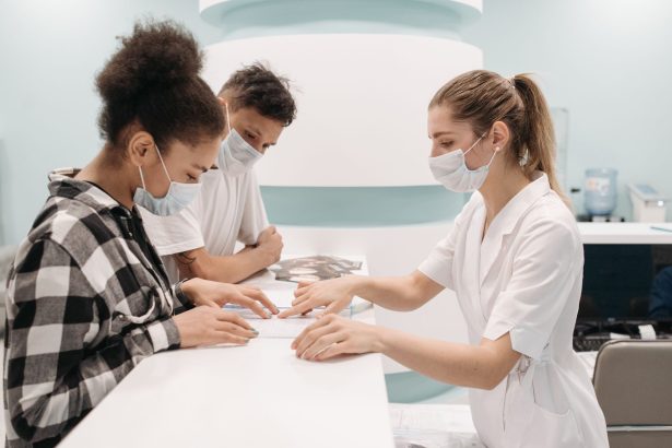 Profissionais de saúde atendem pacientes no balcão de uma unidade médica.